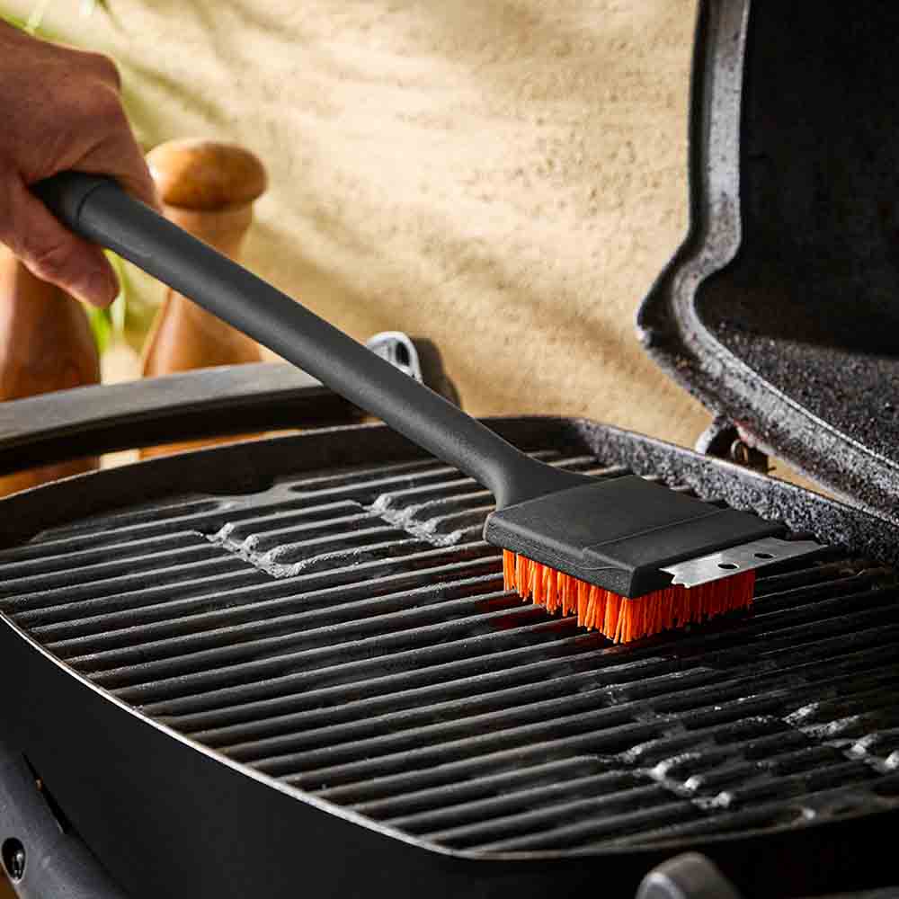 man cleaning BBQ with long handled grill brush - MyHouse