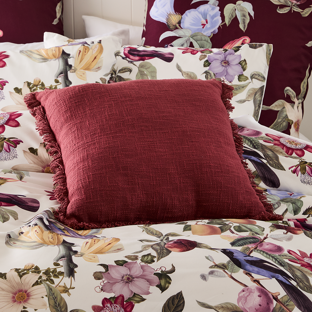 Adorn Living Eva cinnamon cushion with textured woven fabric and fringe trim detailing, styled on blue and mustard check bedding