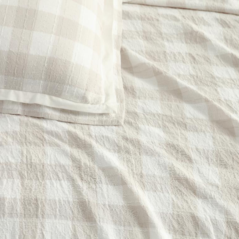 Close-up of beige checkered fabric with a pillow on a white background