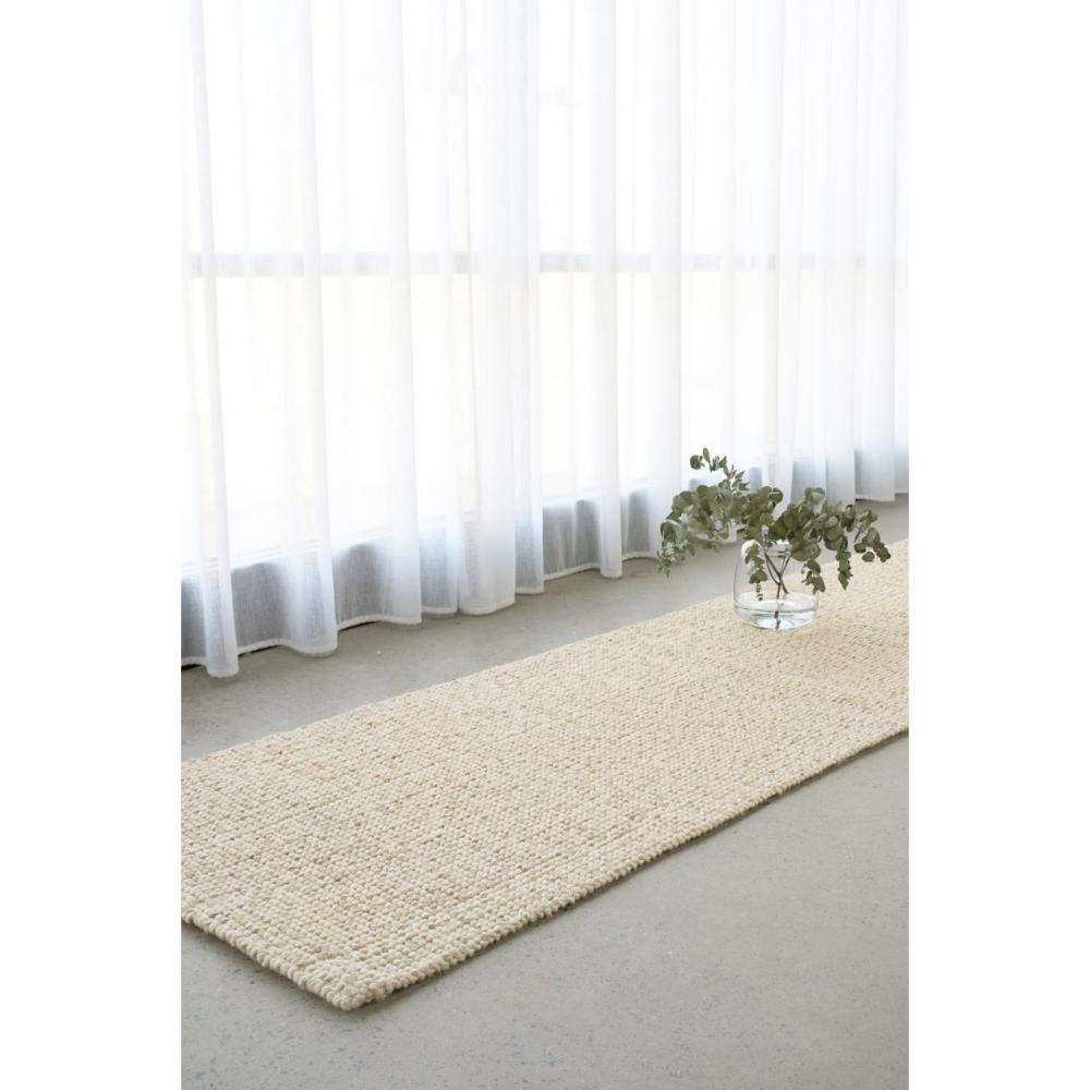 cream beige Hamptons style jute wool rug by a window - MyHouse