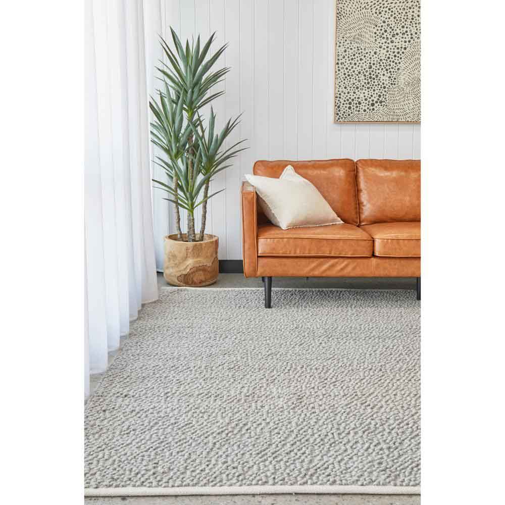 Grey boucle rug with tan leather lounge and plant - MyHouse