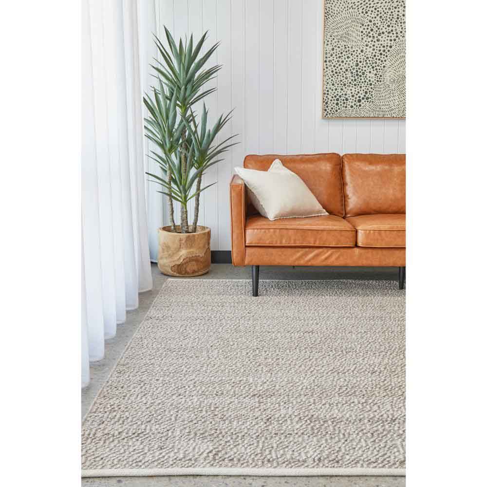 natural beige boucle rug with tan leather lounge and plant - MyHouse