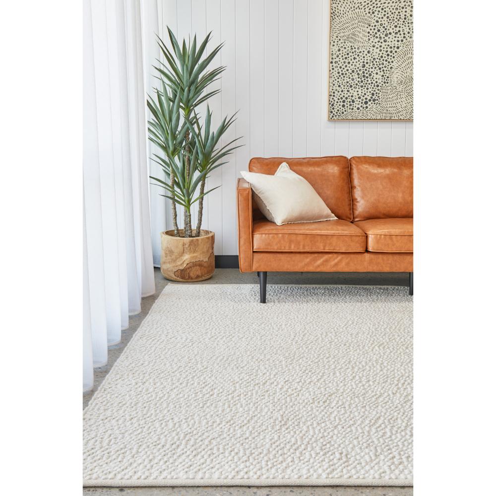white boucle rug with tan leather lounge and plant - MyHouse