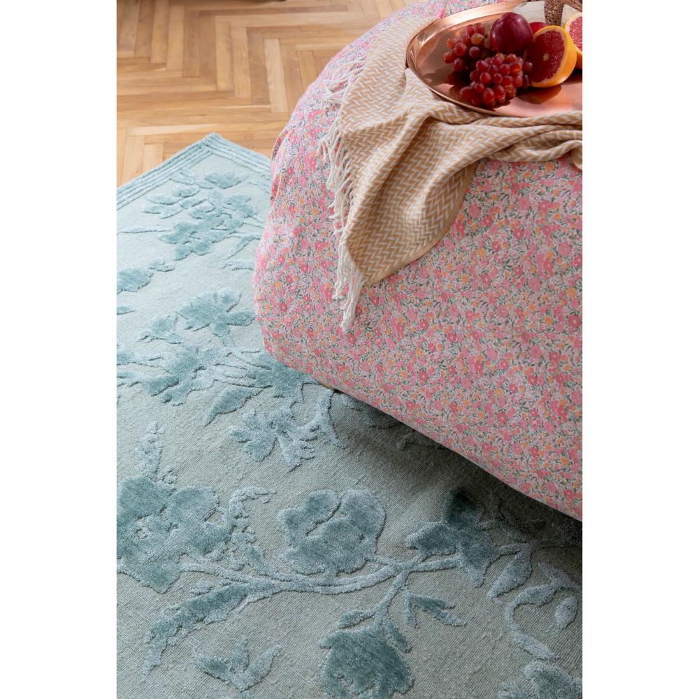 sage green flower rug in bedroom with bed and fruit - MyHouse
