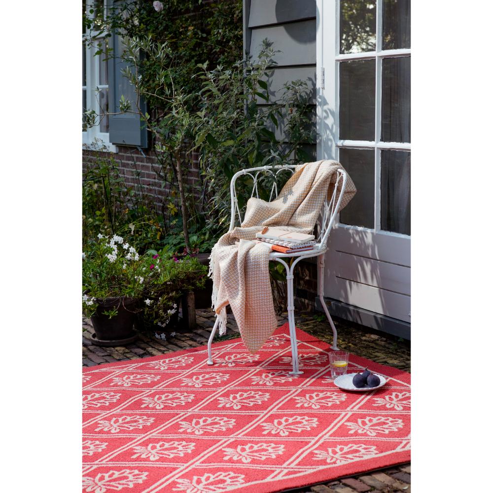 red floral outdoor rug in backyard with chair and throw - MyHouse