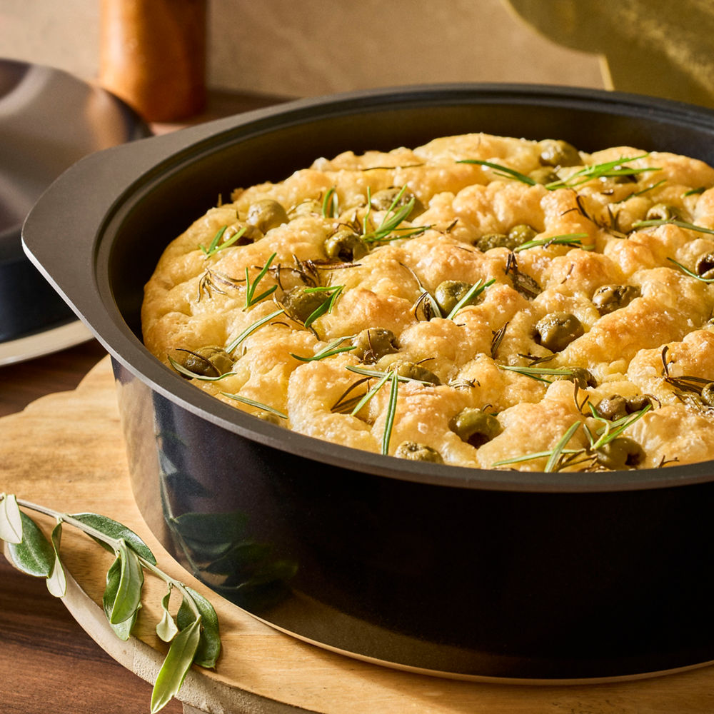 Baked dish with herbs in a black baking dish on a wooden surface