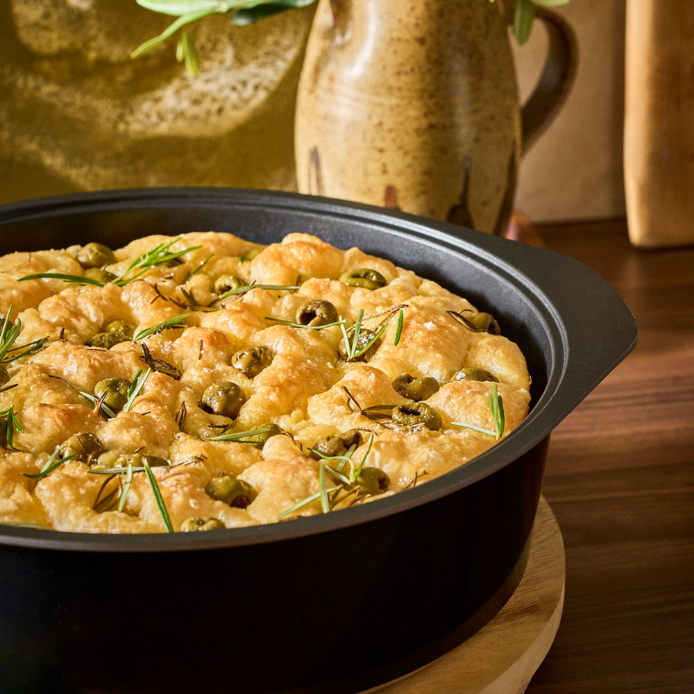 Baked dish with herbs in a black baking dish on a wooden surface