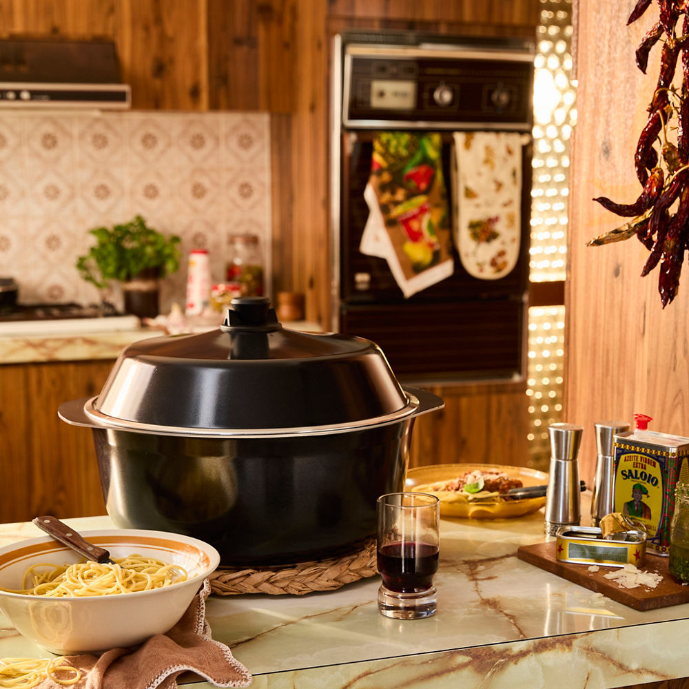 Black pot on a kitchen counter with pasta and a glass of red wine