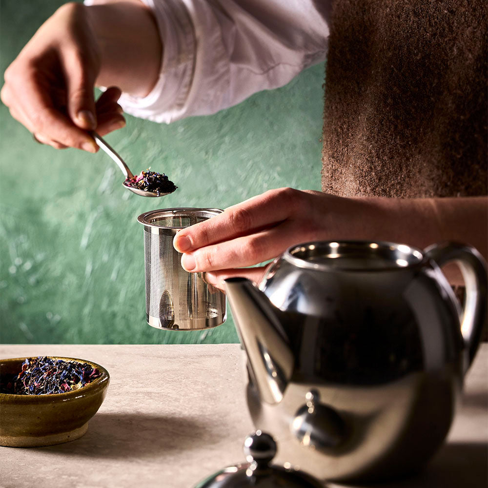 Tea leaves being added to the Barista tea pot, ready for brewing.