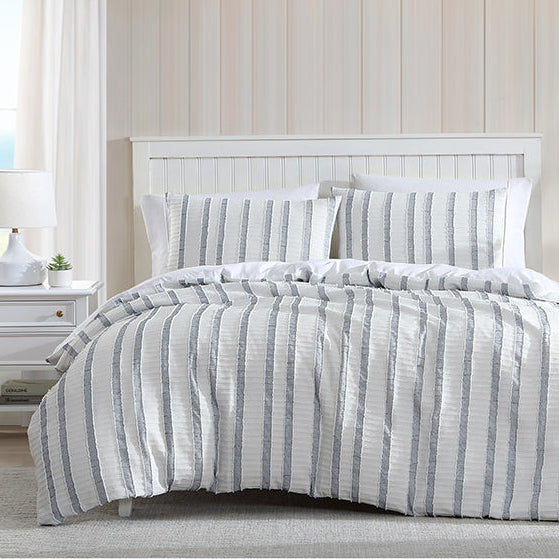 Bed with striped bedding in a room with a window and shelves.