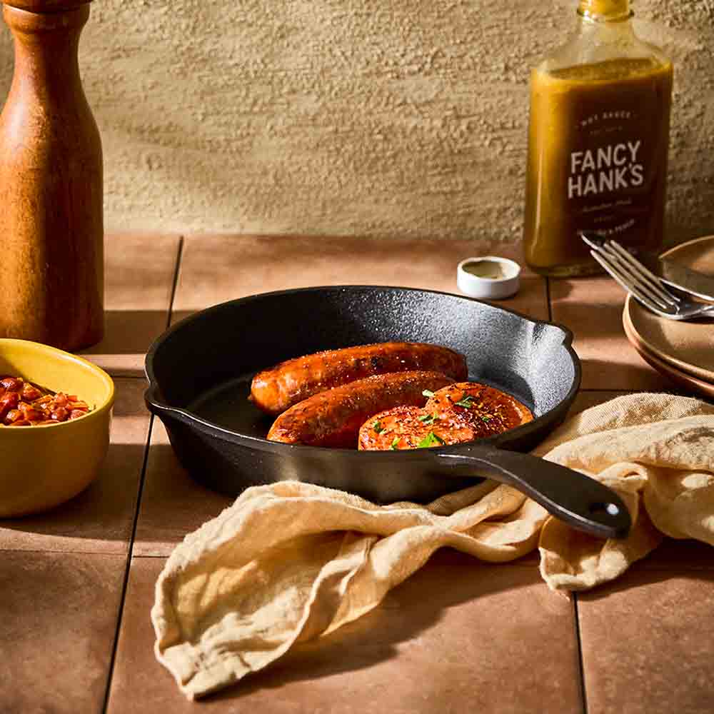 cooked sausages and onions in a cast iron frypan - MyHouse