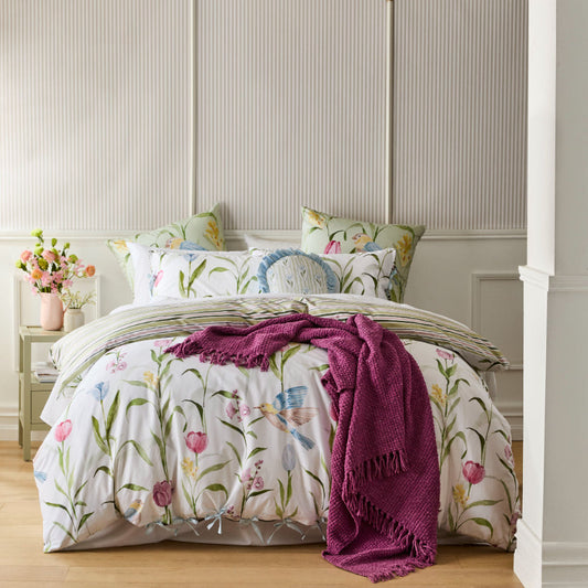 Floral bedding set on a bed with a purple throw blanket in a bedroom setting.