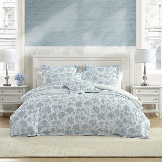 Bedroom with floral bedding on a bed against a blue wall.