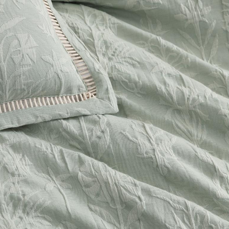 Light green textured comforter with a matching pillow on a white background