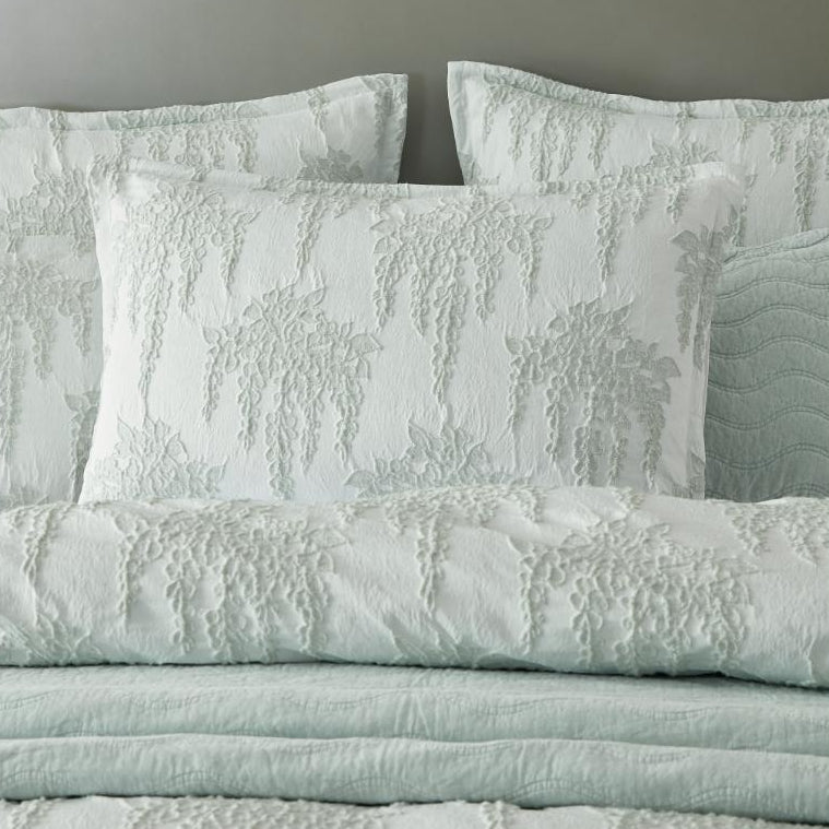 Textured bedding set with matching pillows on a bed with a gray headboard.