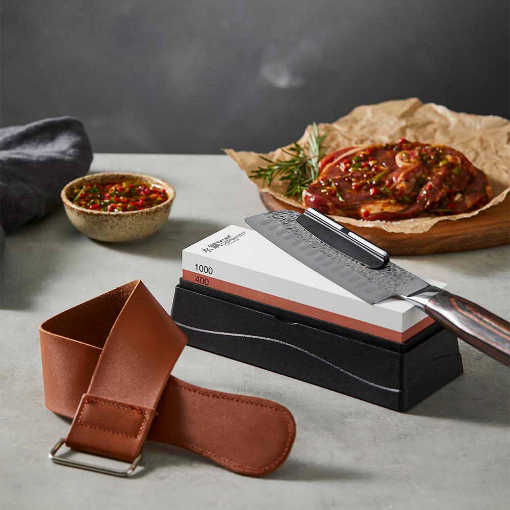 santoku knife sitting on a whetstone with leather strop - MyHouse