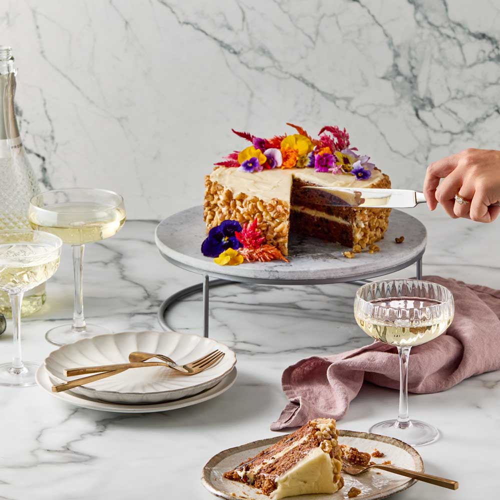 woman cutting slice of cake from marble serving board - MyHouse