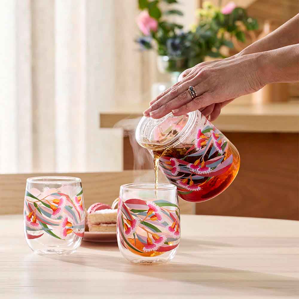 woman pouring tea from a glass teapot into a glass cup