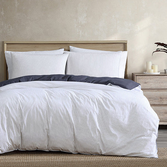 Bedroom with a neatly made bed featuring white bedding and pillows, wooden headboard, and side tables.