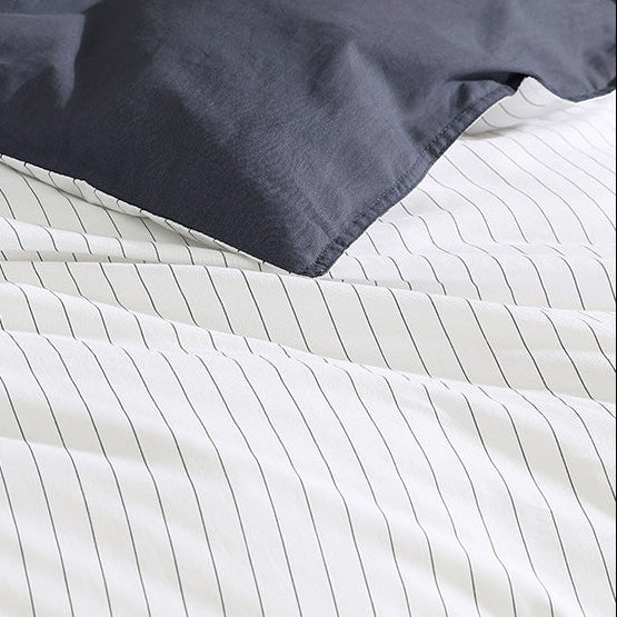 Navy blue comforter on a bed with white striped bedding