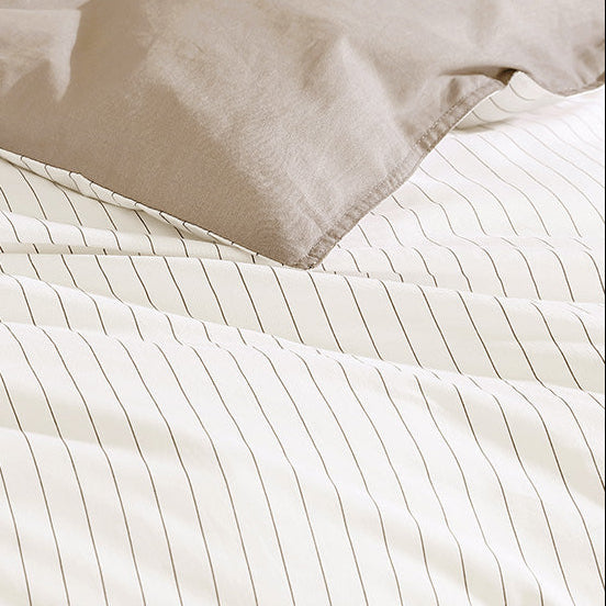 Close-up of beige comforter with white striped pattern on a white background