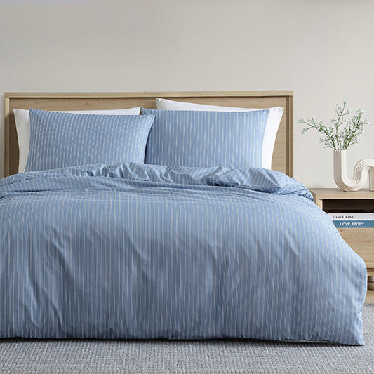 Blue striped bedding set on a bed in a bedroom with neutral decor.