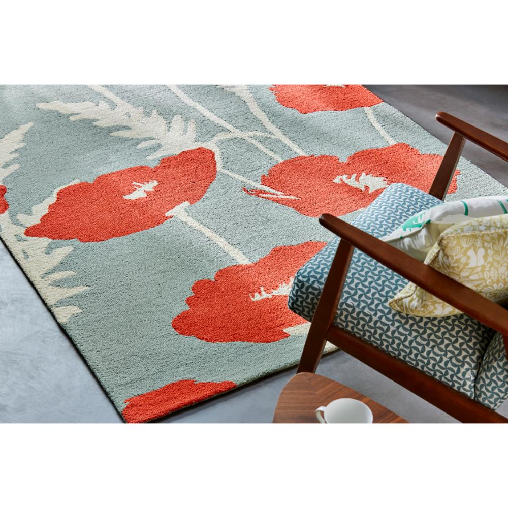sage wool rug with red poppies next to armchair - MyHouse